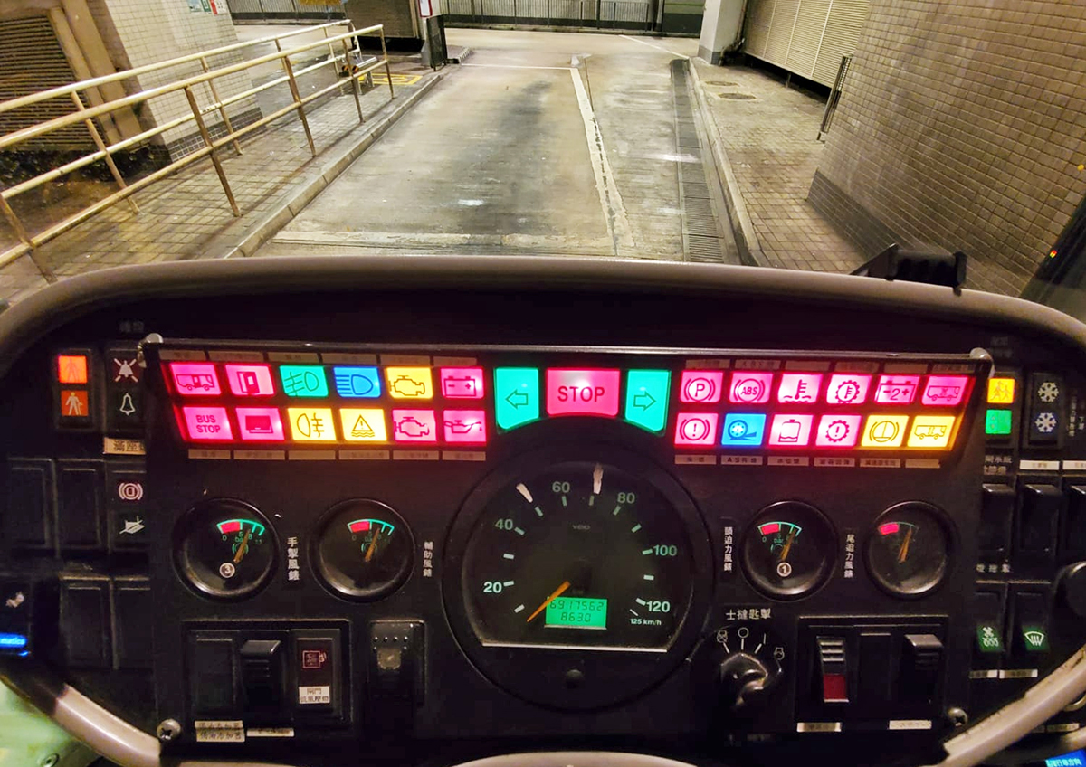 Photograph of the brightly-colored dashboard of a bus from the perspective of the drivers seat.