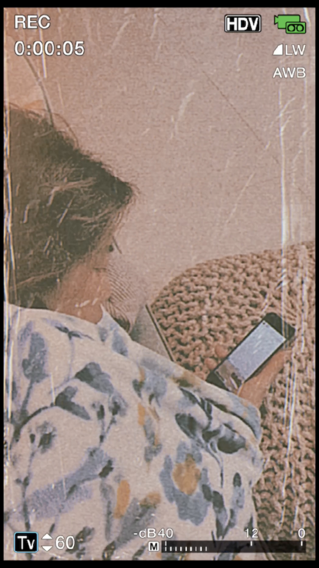 Video recording interface on a cell phone. Woman reclining and looking at a cell phone.