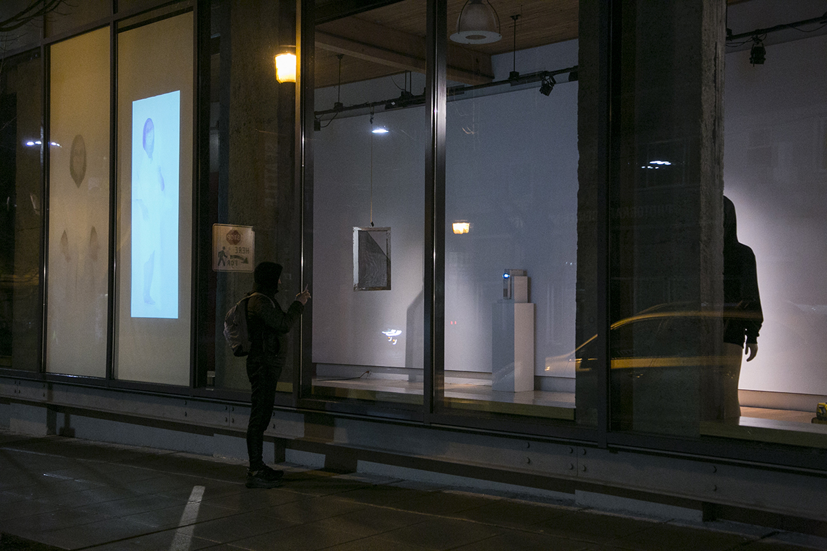 Nighttime street view of artworks by artists D.K. Pan and Christopher Paul Jordan in Hedreen Gallery through 12th Ave windows