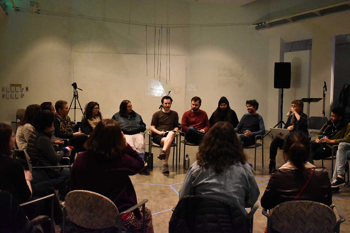 Circle of artists and students discussing performance artwork in Vachon Gallery