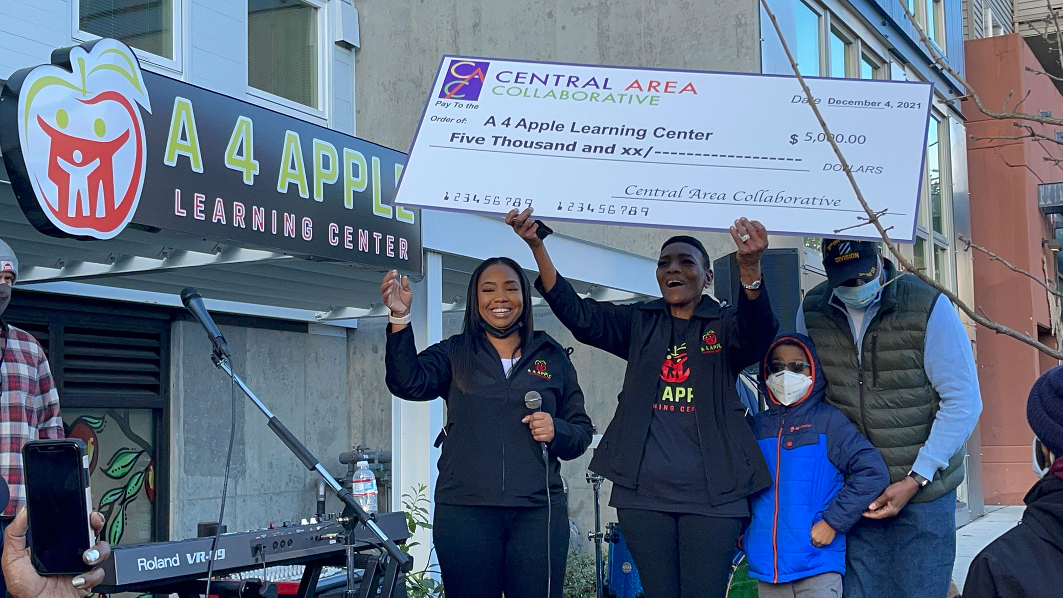 Appollonia Washington, Deborah B. Coleman, and Family are holding a $5000 check in front of their new location during their grand opening event.