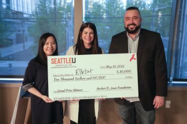 Three people standing holding an oversized check made out to Ellebit for $10,000 from the Harriet Stephenson Business Plan Competition in May 2022