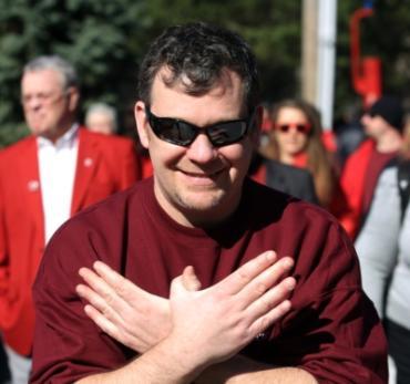 Mike Mullen, alum, showing the Redhawk sign with hands.