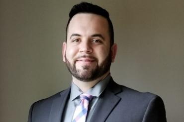 Justin's headshot, wearing suit and tie