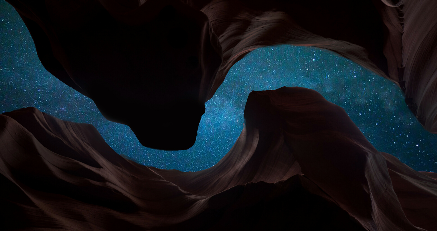 a view of the night sky from between dark red rocks of the grand canyon rising up