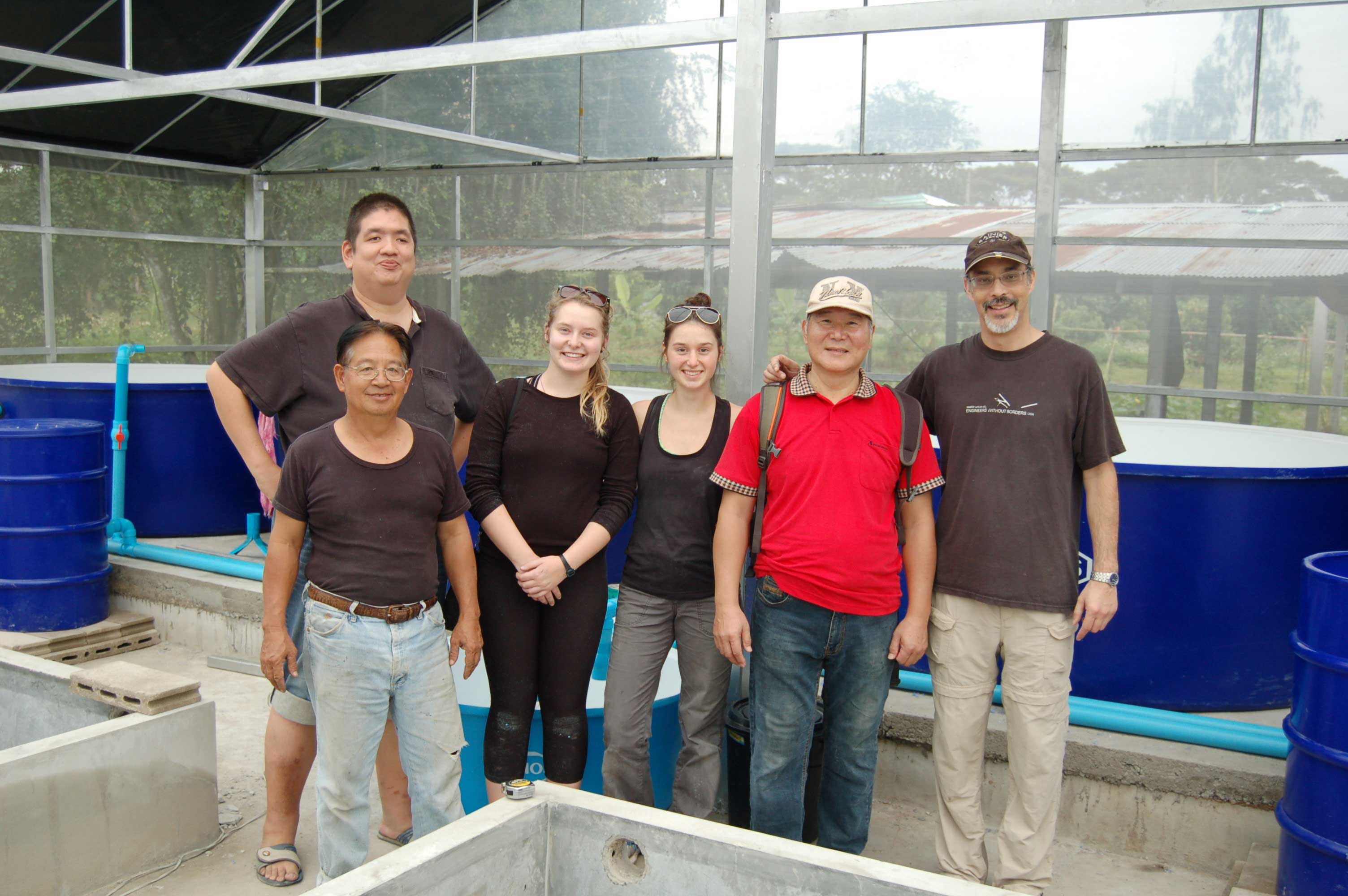 'Aquaponics in Thailand' team with completed water tanks and piping system in background