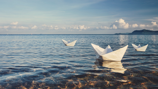 Three paper sailboats near the ocean shore
