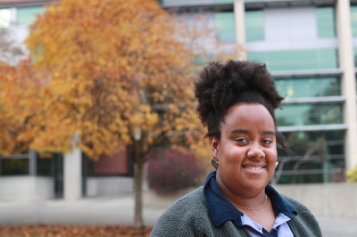 Student Serena Oduro standing in front of fall trees