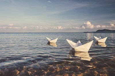 Three paper saliboats floating offshore
