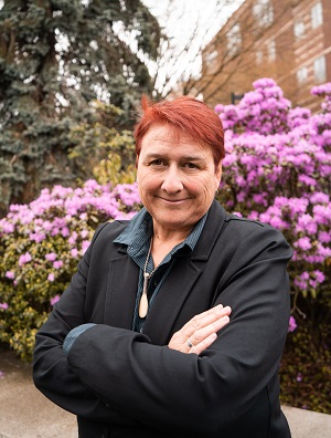 Photo of Dr. Kirsten Thompson in front of flowering shrubs