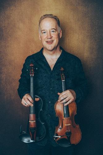 Middle aged man holding two violins