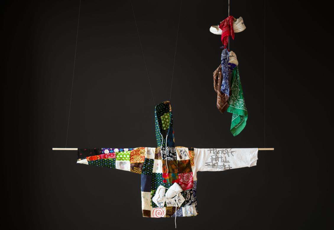 a quilted shirt suspended before a black wall