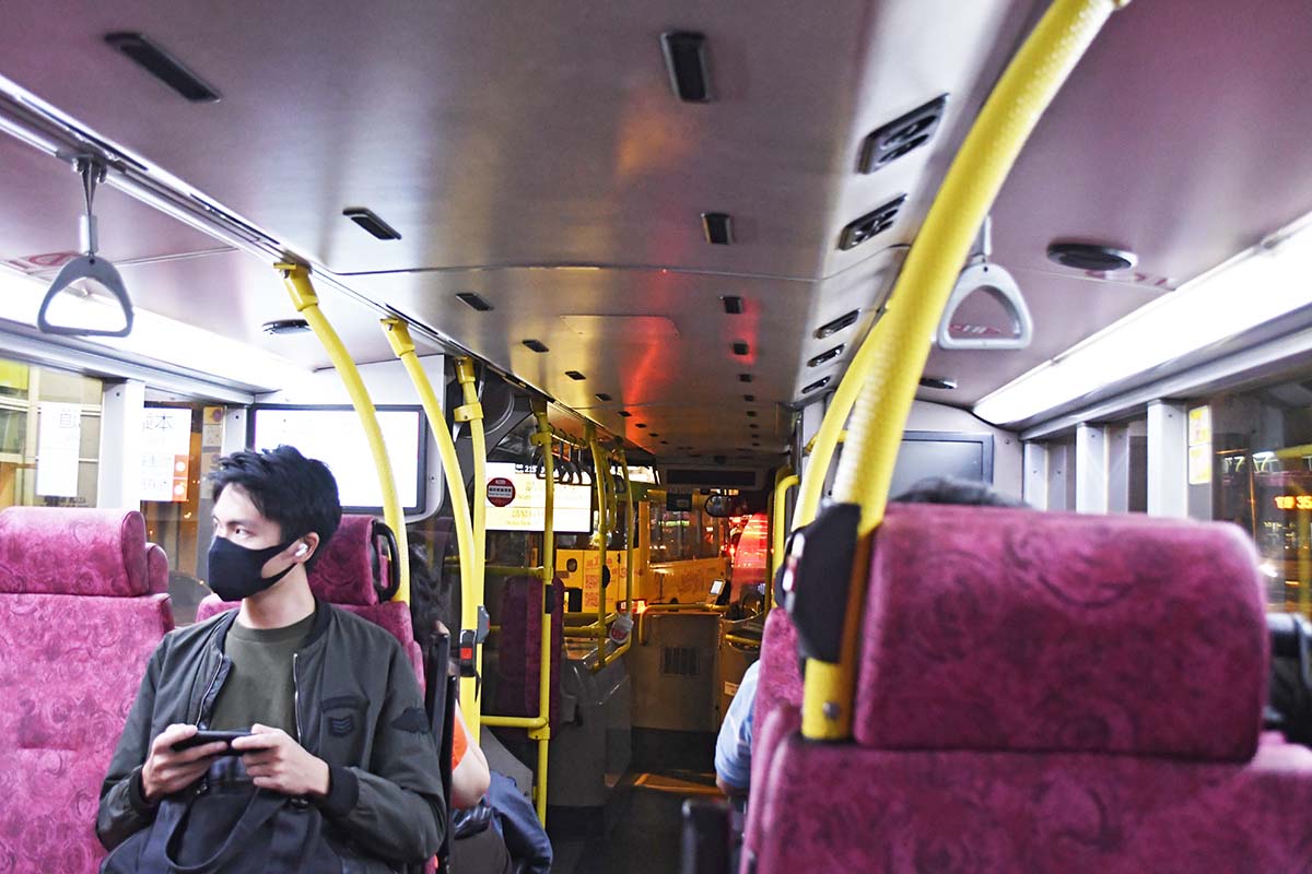 a person looking to the left out a window on a bus with plush seats