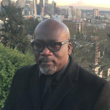 Picture of Saheed Adejumobi, Professor of History, photo is him with the Seattle skyline in the background.