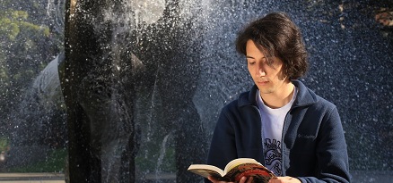 Student reading by fountain