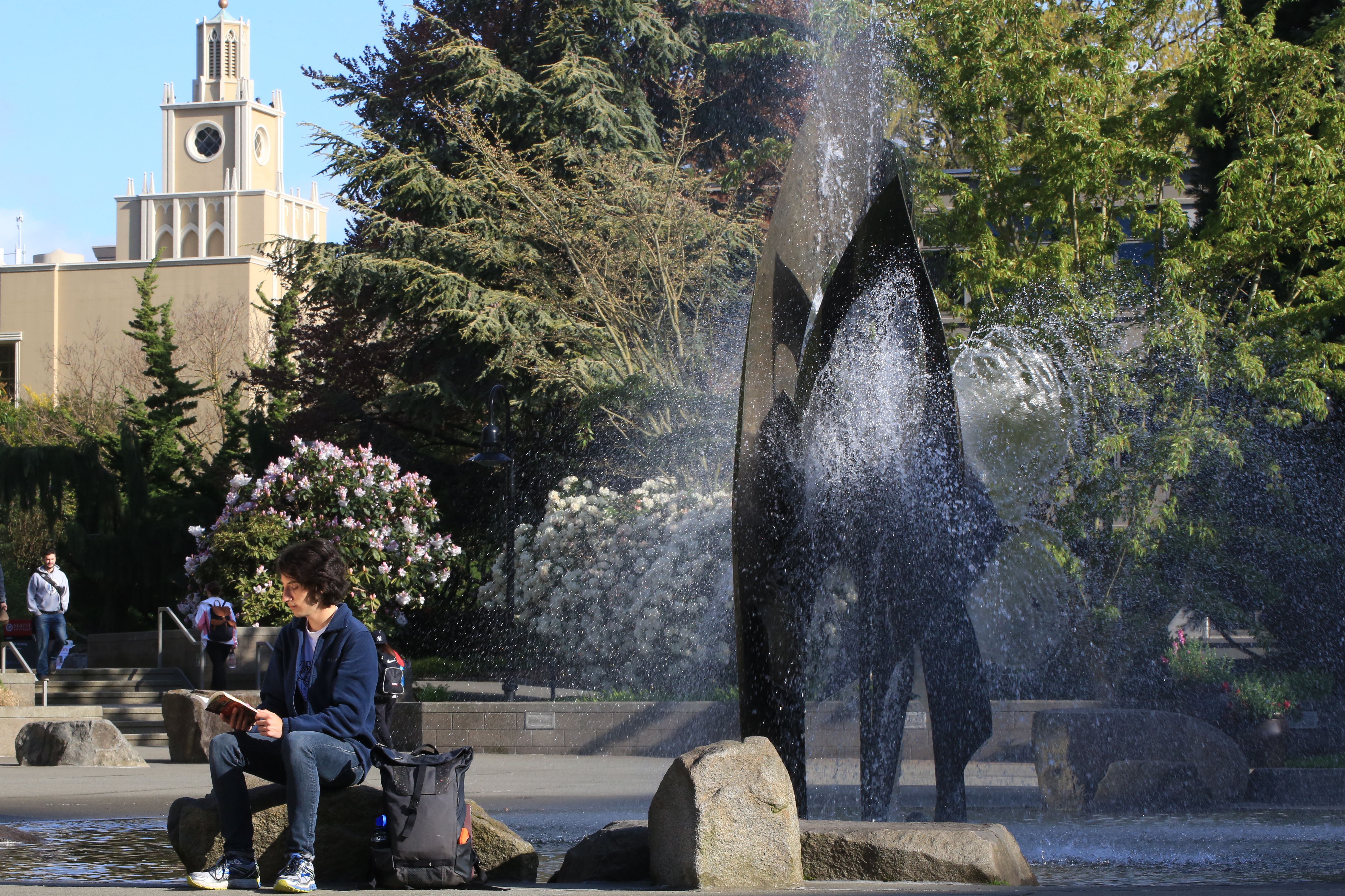 Student reading a book in front of fountain in SU quad