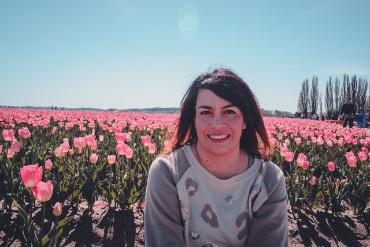Student posing in front of a field of pink tulips 
