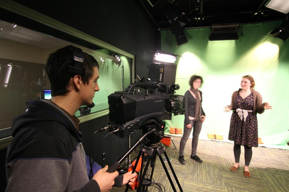 Male student filming two female students in the studio
