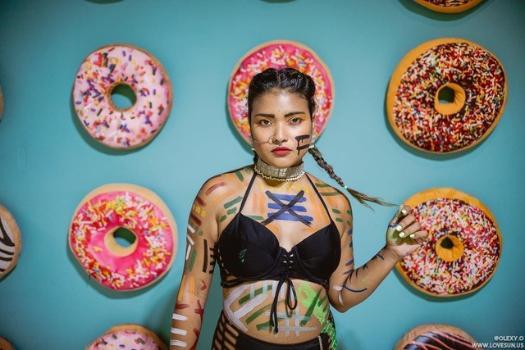 Rohena Alam Khan standing in front of a vibrant print of large colorful donuts