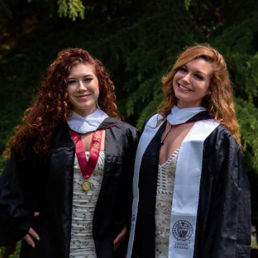Amber and Eva standung together in thier commencement gowns