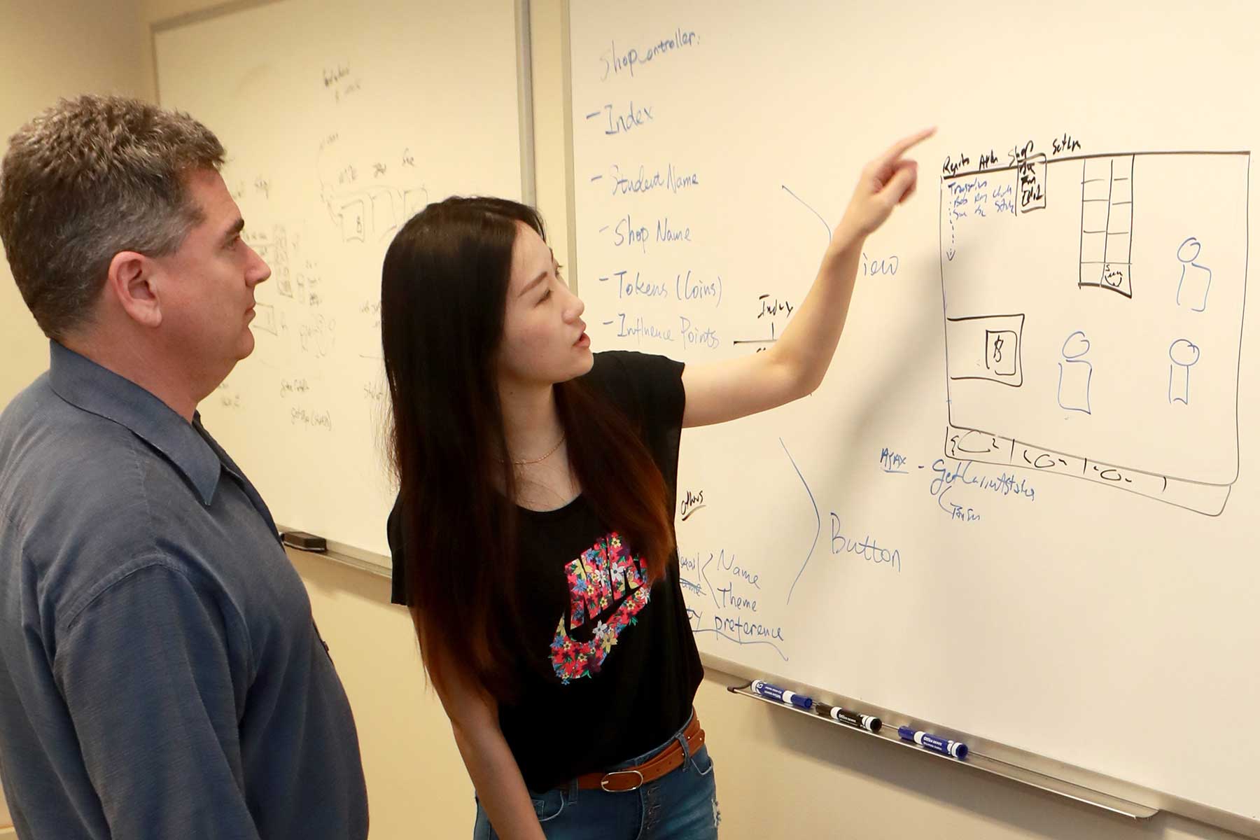 Professor Mike Koenig at the whiteboard with a student