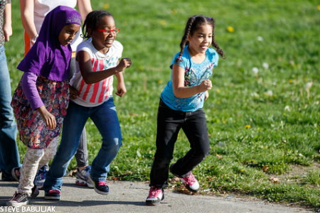 3 Bailey Gatzert Elementary School students running next to a grassy field