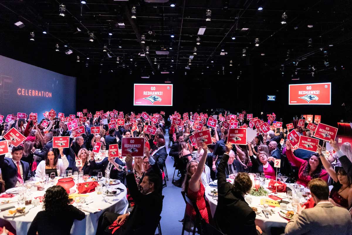 Red Tie alumni event with people holding up bidding paddles.