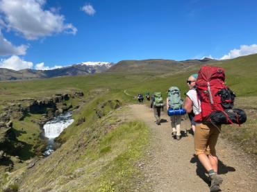 Hikers on a trail next to a waterfall