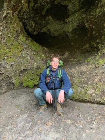 A student in front of mossy rocks.