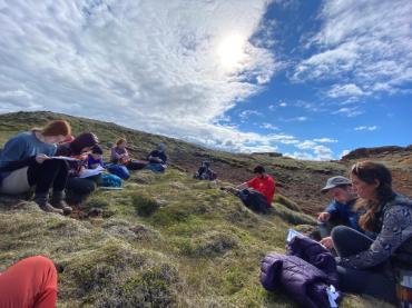 A group of students sitting on a bed of moss