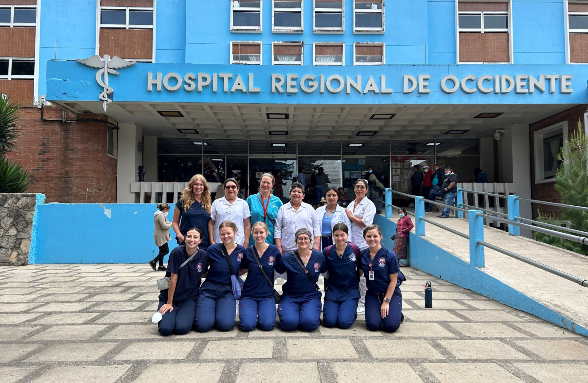 12 people posing in front of a hospital