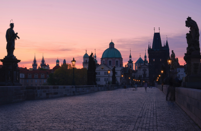 People walking along Charles Bridge at sunset