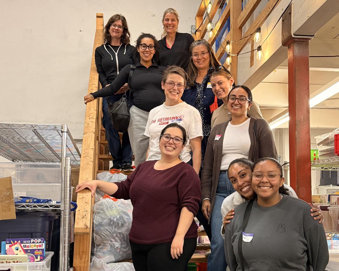 A group of alumni stand on stairs at WestSide Baby volunteering event