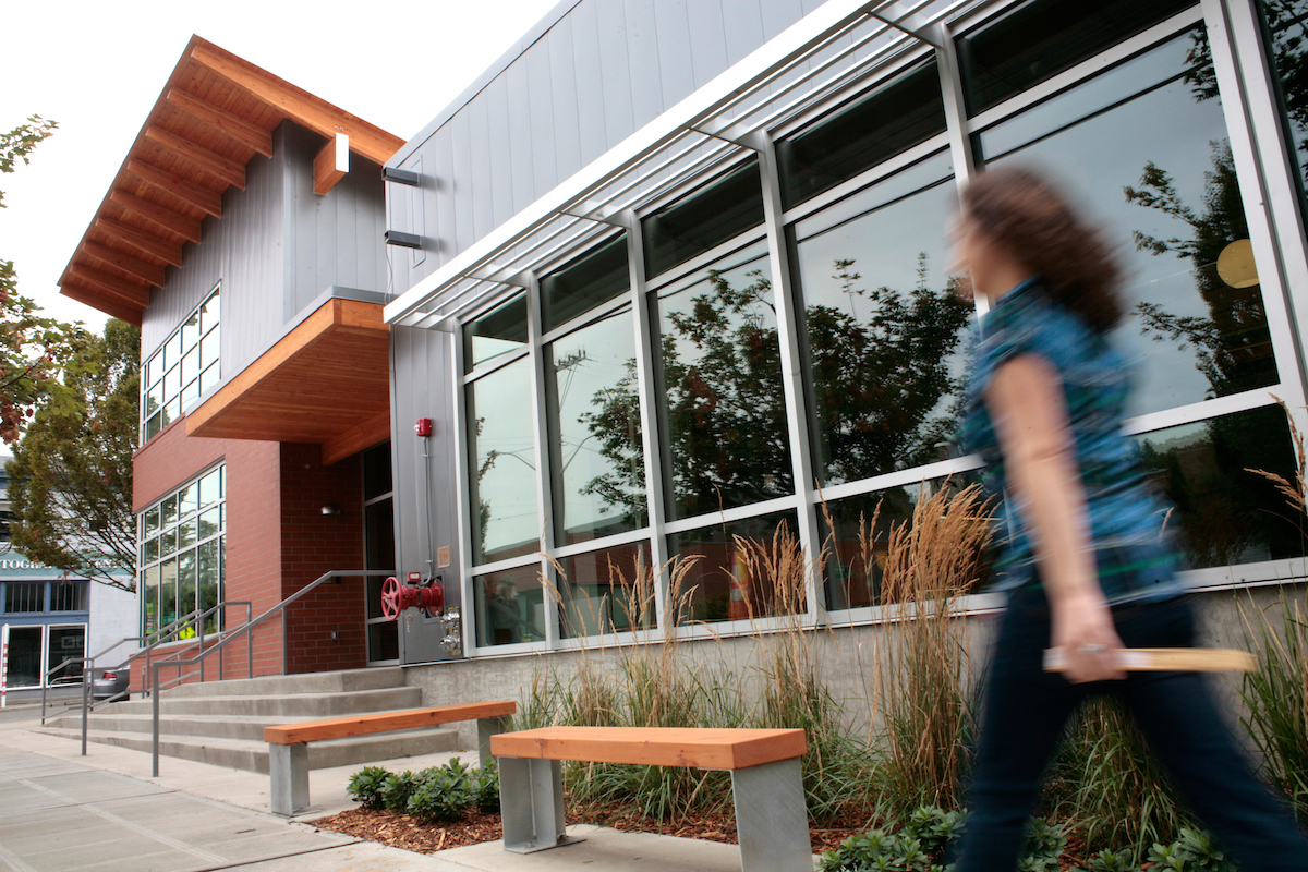 Exterior of Alumni and Admissions Building with a figure walking by quickly.