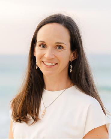 Meg Blattner smiling in front of blurry ocean sky background