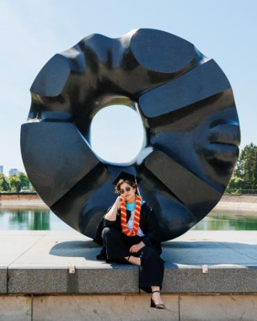 Erin Kwan in graduation garb in front of art