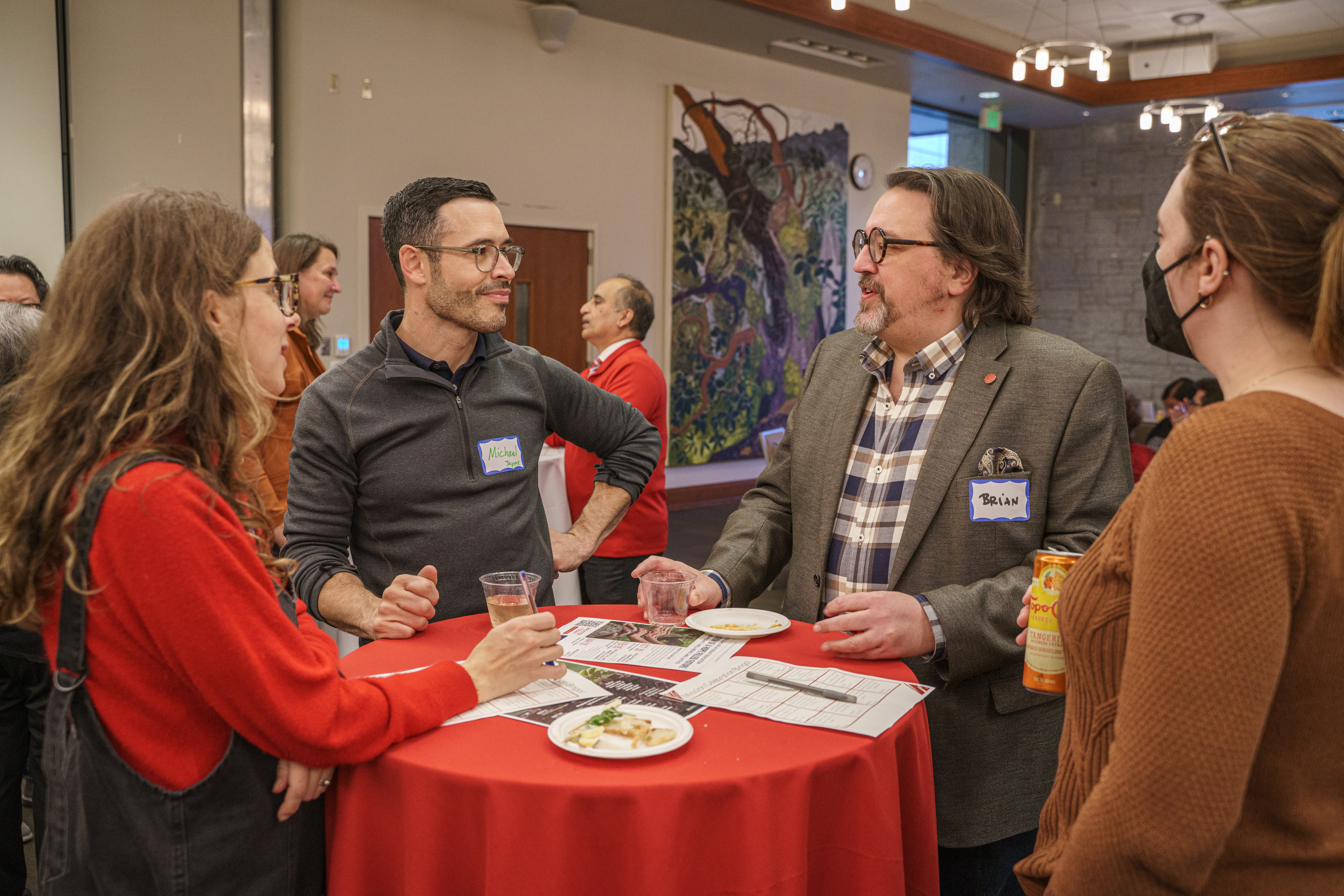 Staff and faculty standing at a round table discussing.