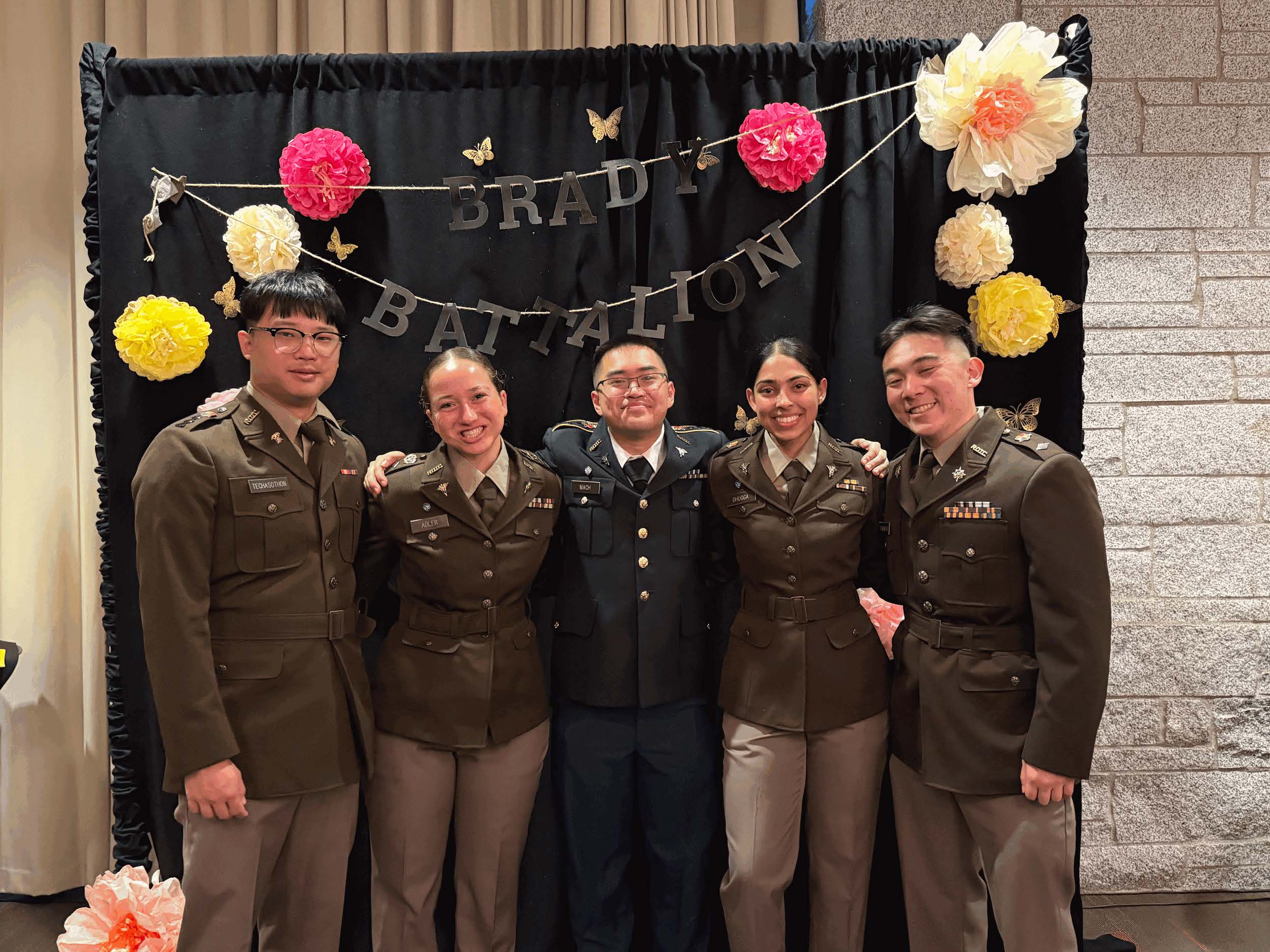 Cadets in uniform in front of photo wall