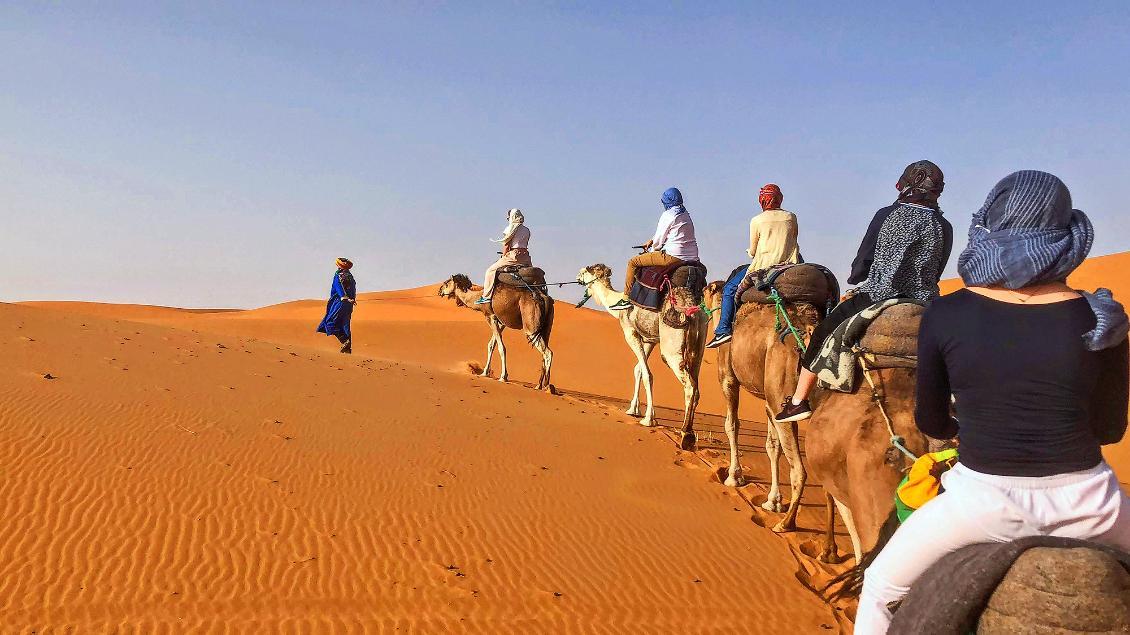 A group of people riding camels through the desert.