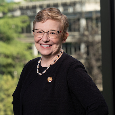 Maura Mast posing in front of a window overlooking campus