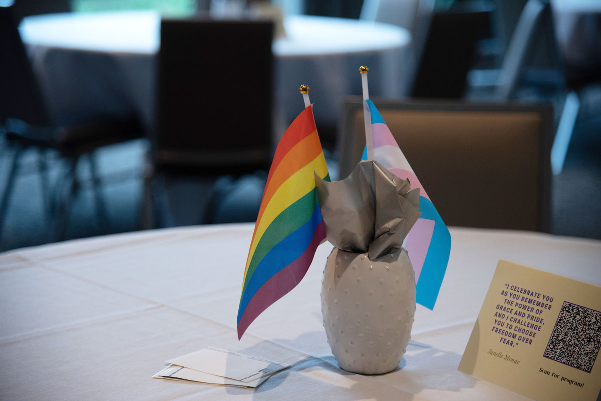 A six-color Pride flag and a Transgender Pride flag within in a table centerpiece vase.