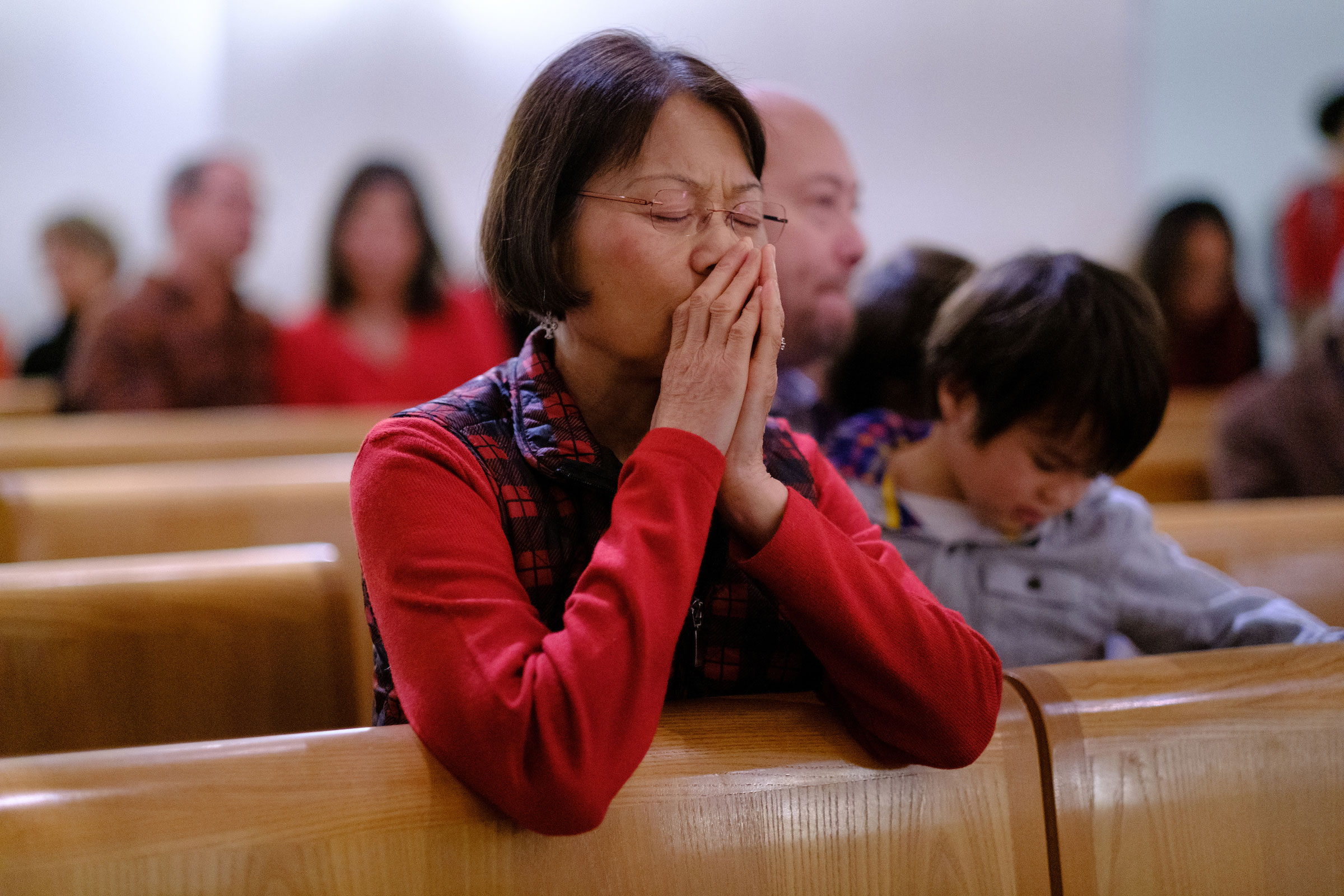 a woman sits in prayer with her eyes closed at the Advent Mass