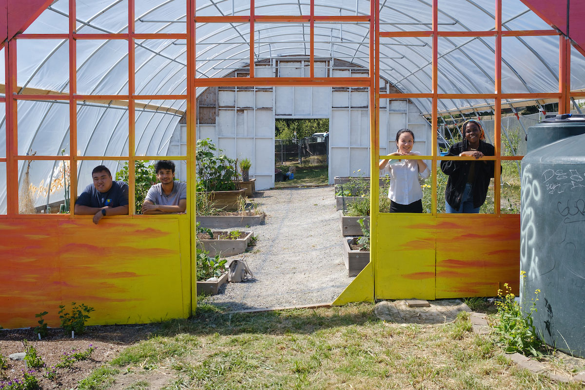 Four students stand next to the solar energy panels created at Yesler Terrace