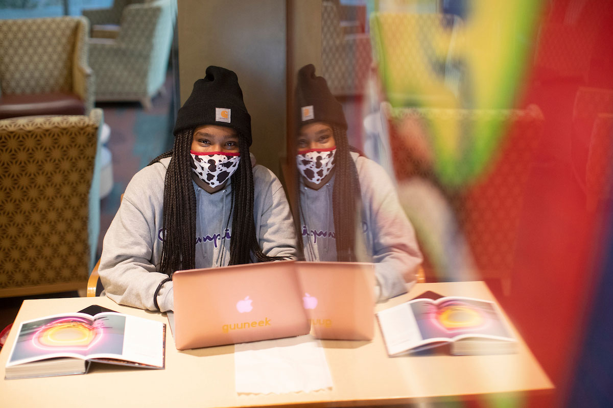 Student with mask on studying in library