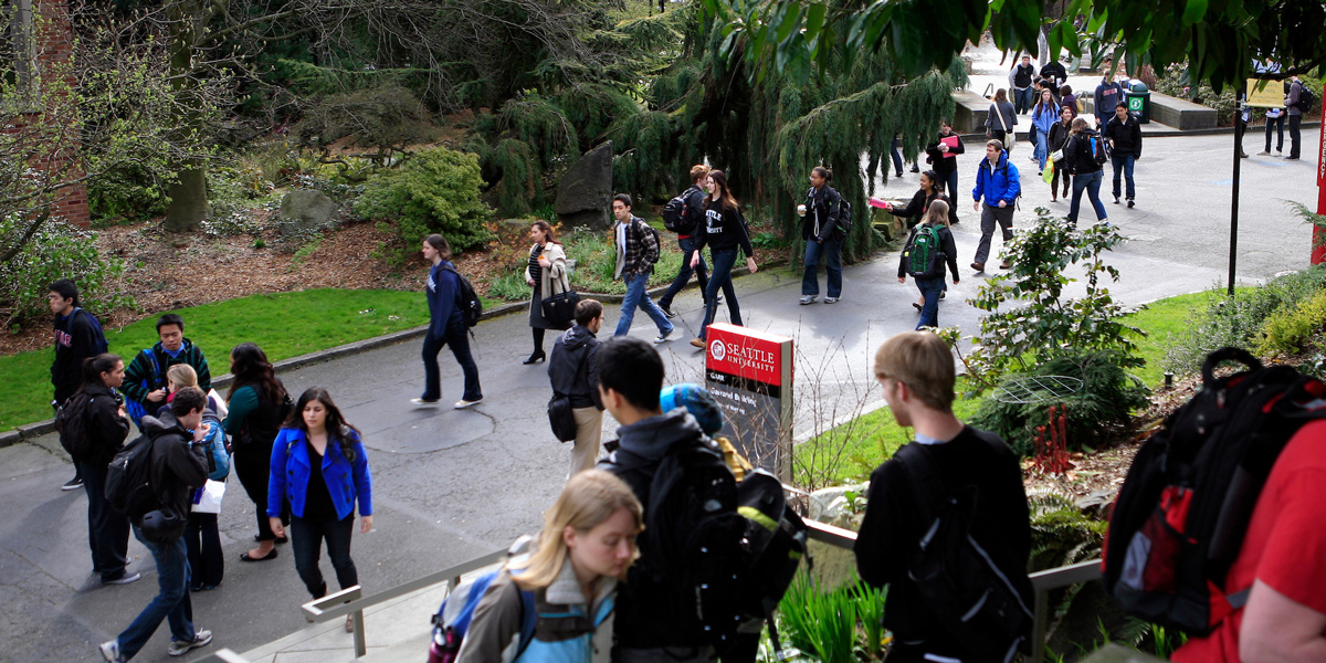 a crowd of students walking through campus between classes