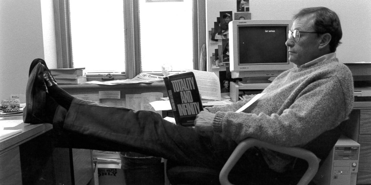 George Kunz leaning back in a chair reading the book "Totality and Infinity"