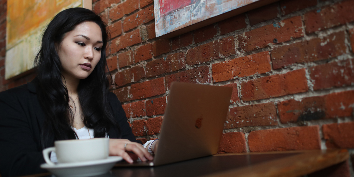 Seattle U student working on a laptop at a coffee shop