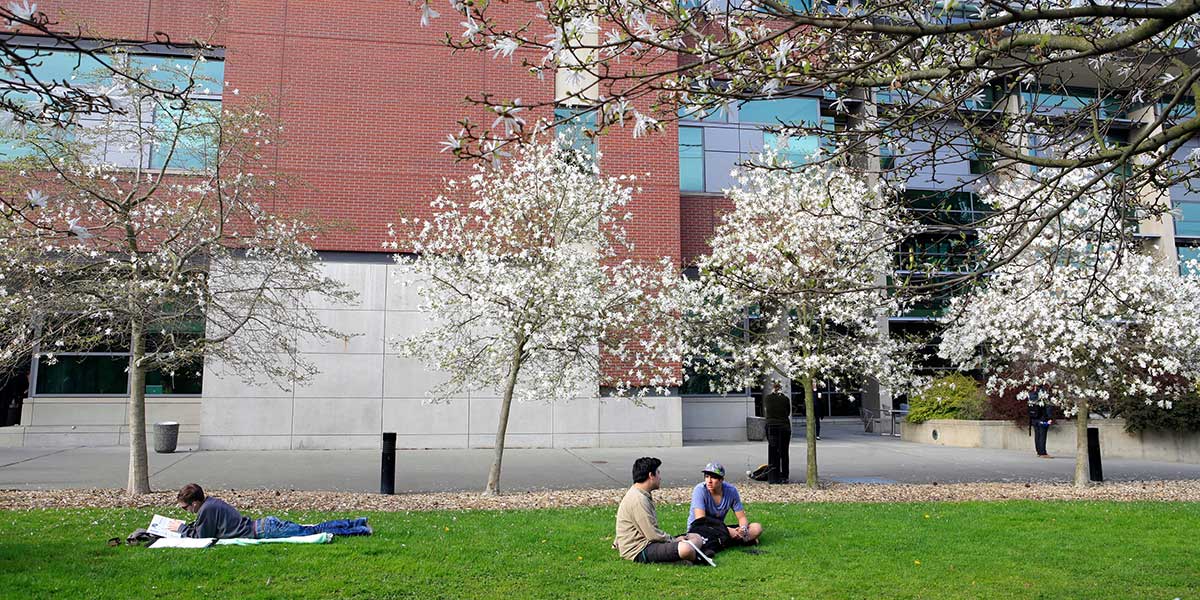 Students sitting on the grass in front of Seattle University School of Law