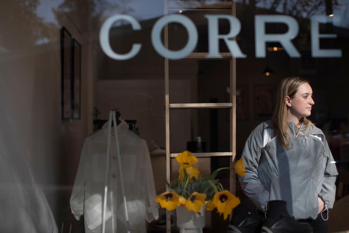 Photo of alumna Desi Caswell standing behind a window at a downtown Seattle store, Corre.