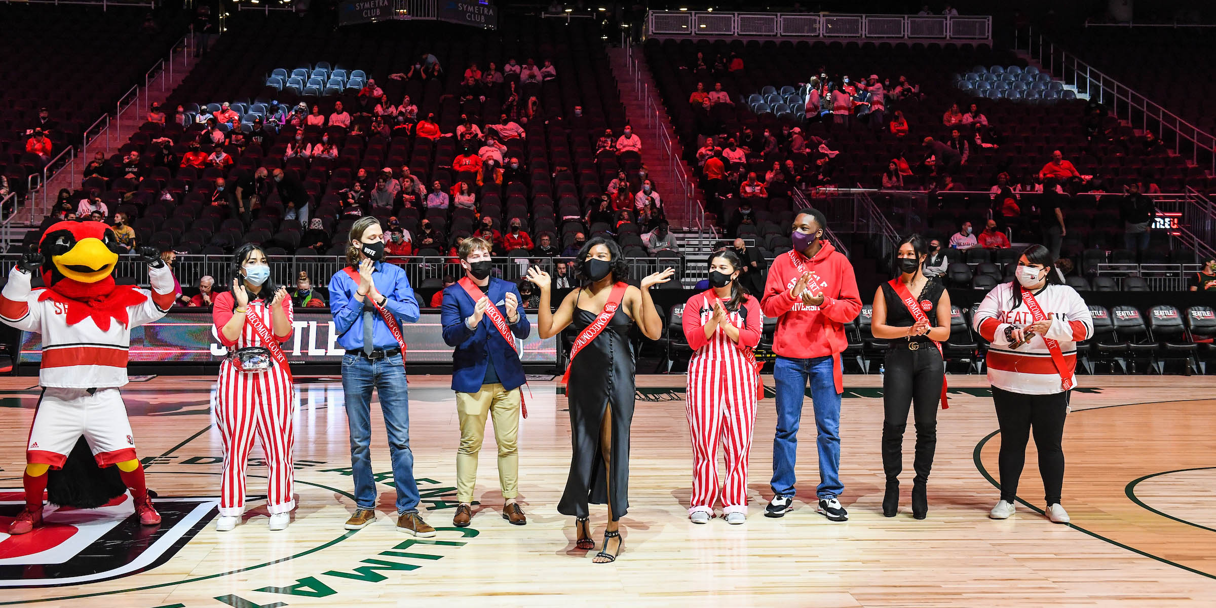 Group standing alongside Seattle University mascot, Rudy the Redhawk, in center of basketball court at Climate Pledge Arena during SU Homecoming 2021.